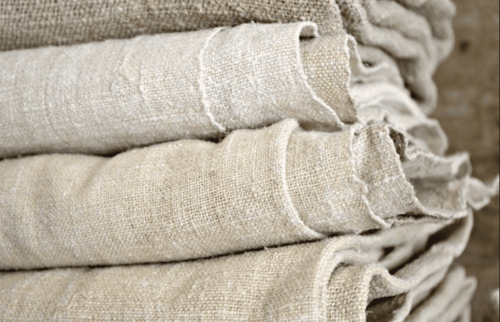 Sustainable Interior Design image of folded pile of natural linens in varying shades of white and beige