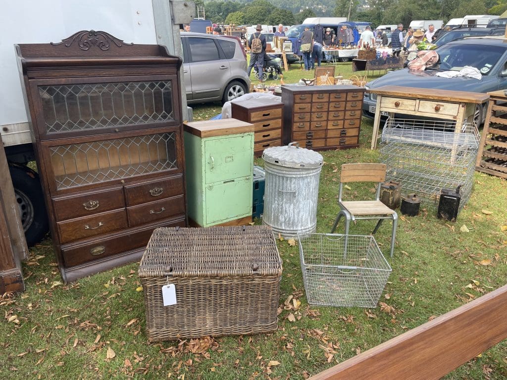 Vintage furniture and decor found at Malvern Flea Market including wire frame basket, wicker trunk and old school wooden chair