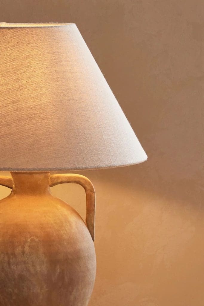 Terracotta urn-style table lamp with handle and a cream lampshade