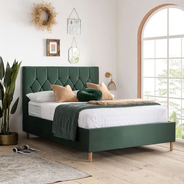 Forest green upholstered bed with tufted diamond pattern headboard, white bedding and plant styling