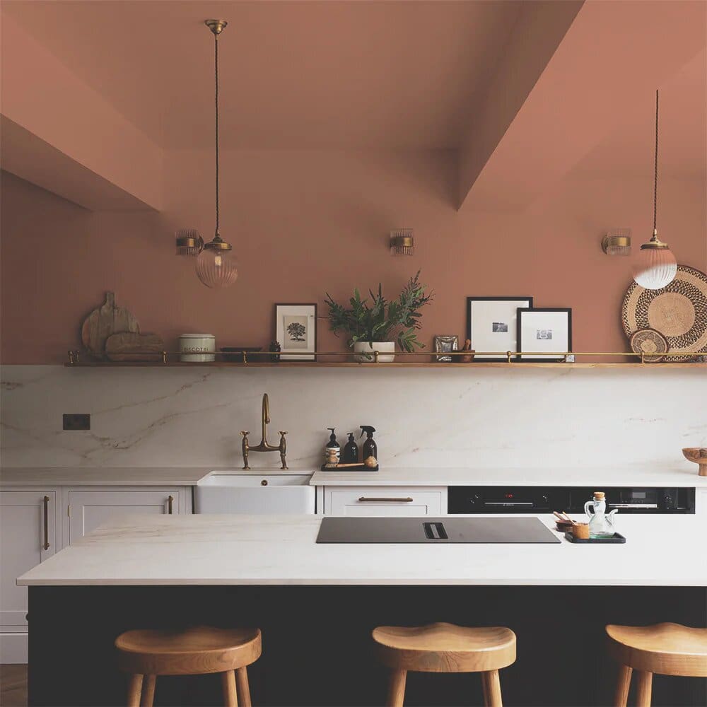 Modern kitchen with warm white marble worktops and splashback, antique brass hardware and painted terracotta walls and ceiling