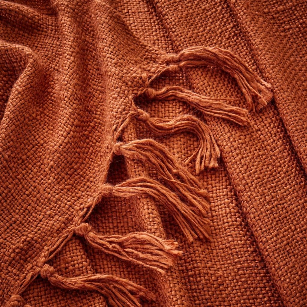 Woven and tasselled throw in a rich terracotta