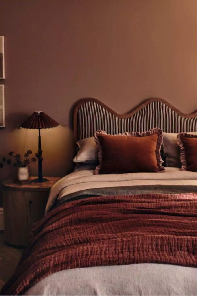 Tonal terracotta styled bedroom with terracotta walls, bedding a dark red-brick colour throw and cushions