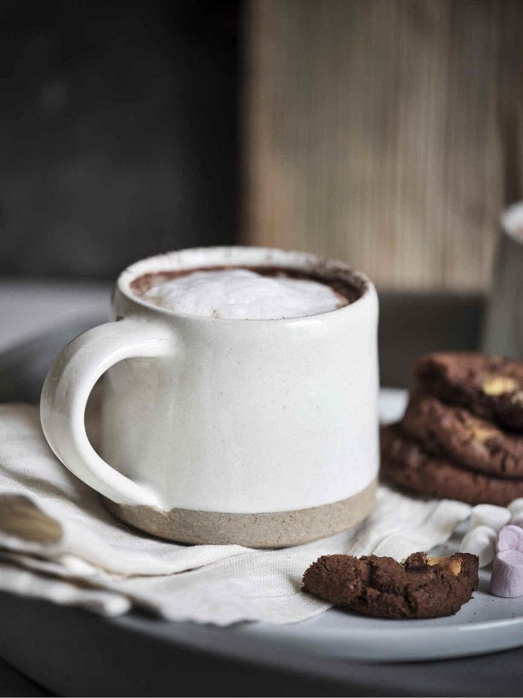 Hand-made white ceramic coffee mug with double-chocolate cookies for the ultimate treat.