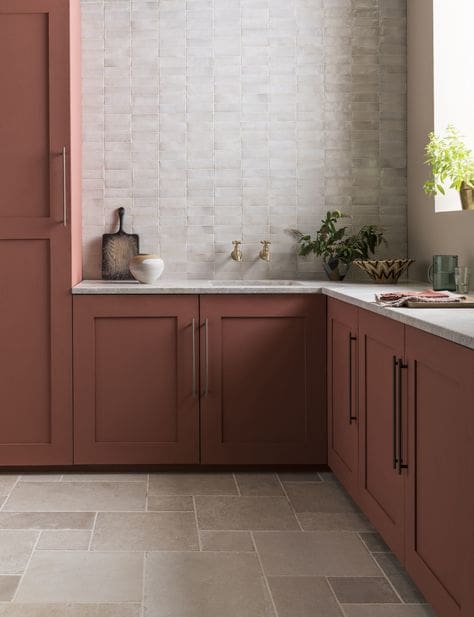 Red clay kitchen cabinetry with nuetral stone flooring and wall detailing