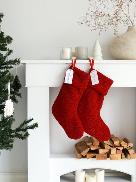 Bright redstockings hung from white mantel and fireplace