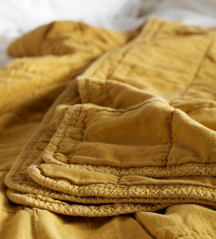 Ochre yellow quilted throw reflecting sunset shades and yellow tones