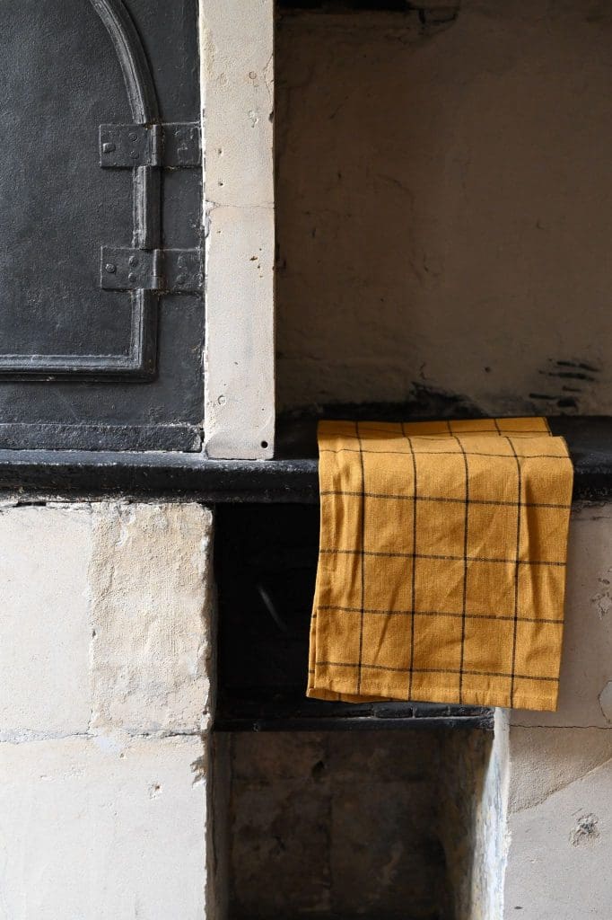 Old fashioned bread oven with concrete counter and mustard-yellow and black checked tea towel