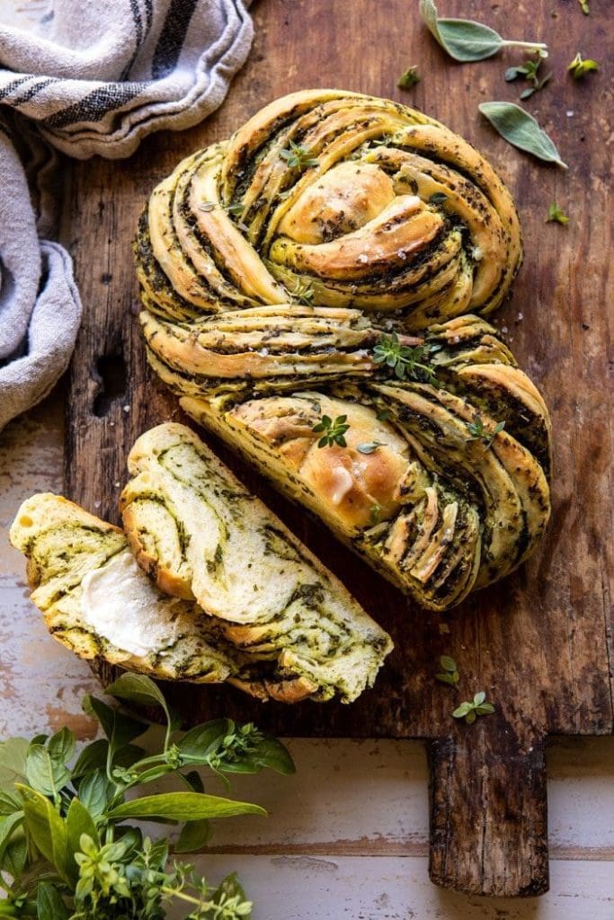 swirled pattern baked bread loaf on a dark wood vintage board and fresh basil leaves