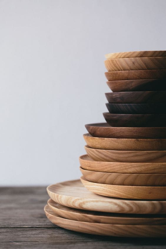 Stack of wooden plates ranging from large to small in varying wood finishes and colours